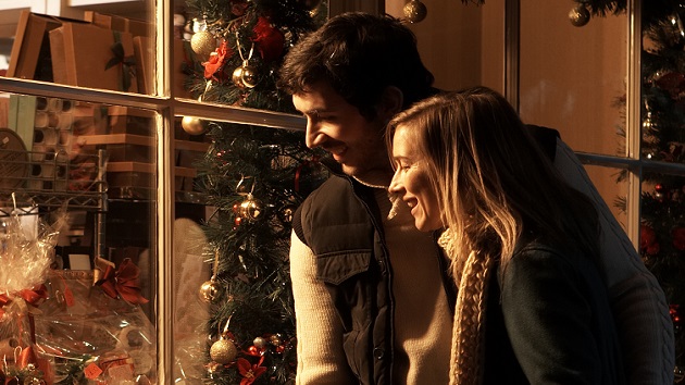 Young couple looking at Christmas display in shop, smiling