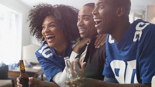 Friends drinking beer and cheering at game on television